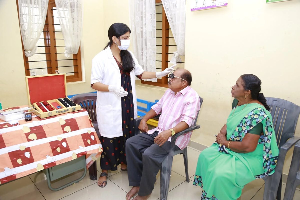 A doctor checking an elderly patient’s eyesight during a home visit